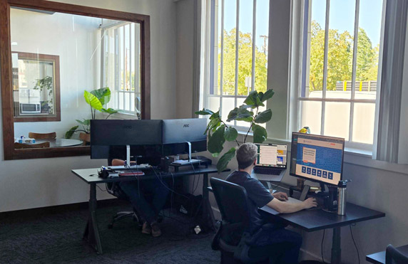Digital marketing team optimizing web design on dual monitors, focusing on UX/UI development and SEO strategies.
